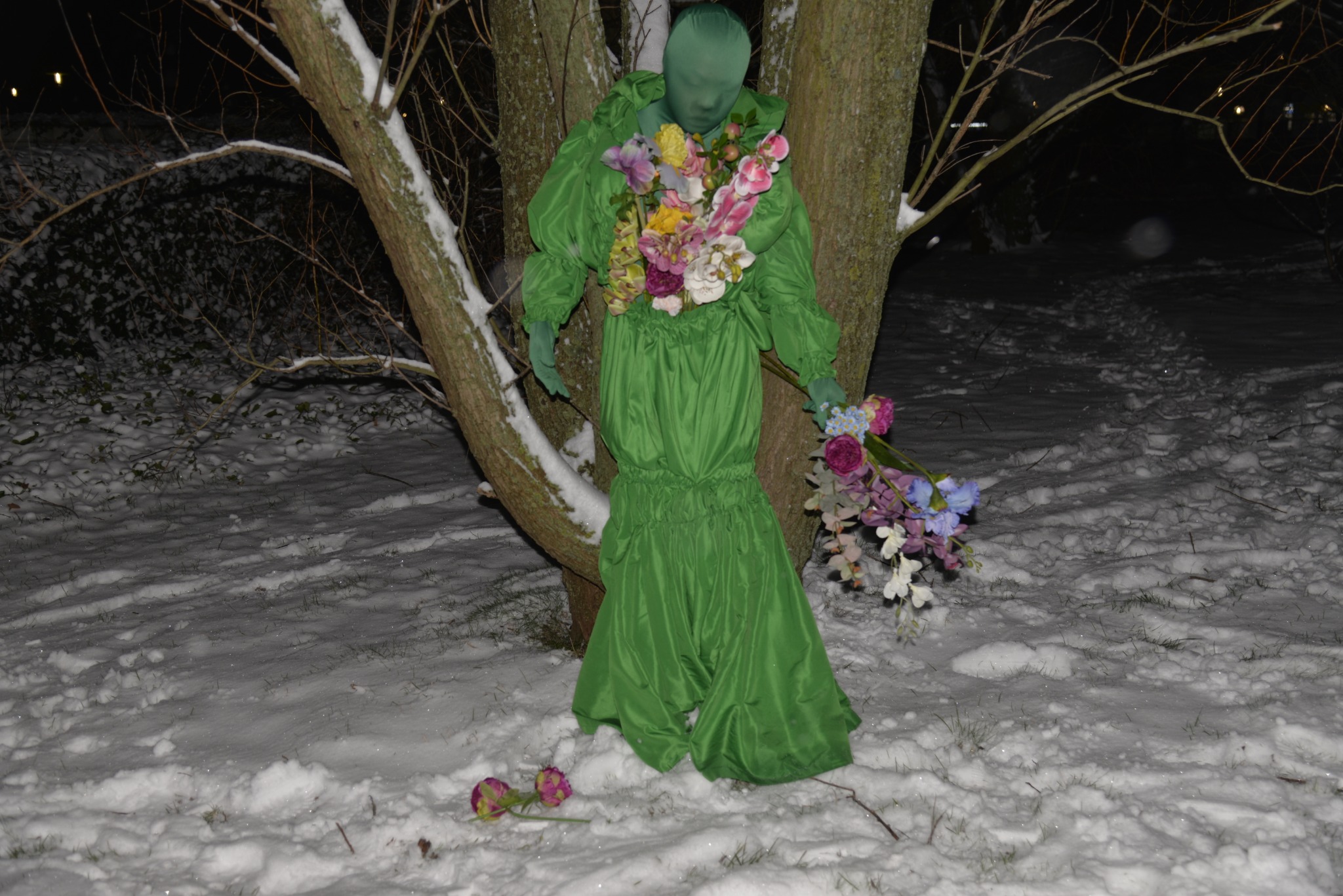 Flower goddess in a green costume carrying plastic flowers