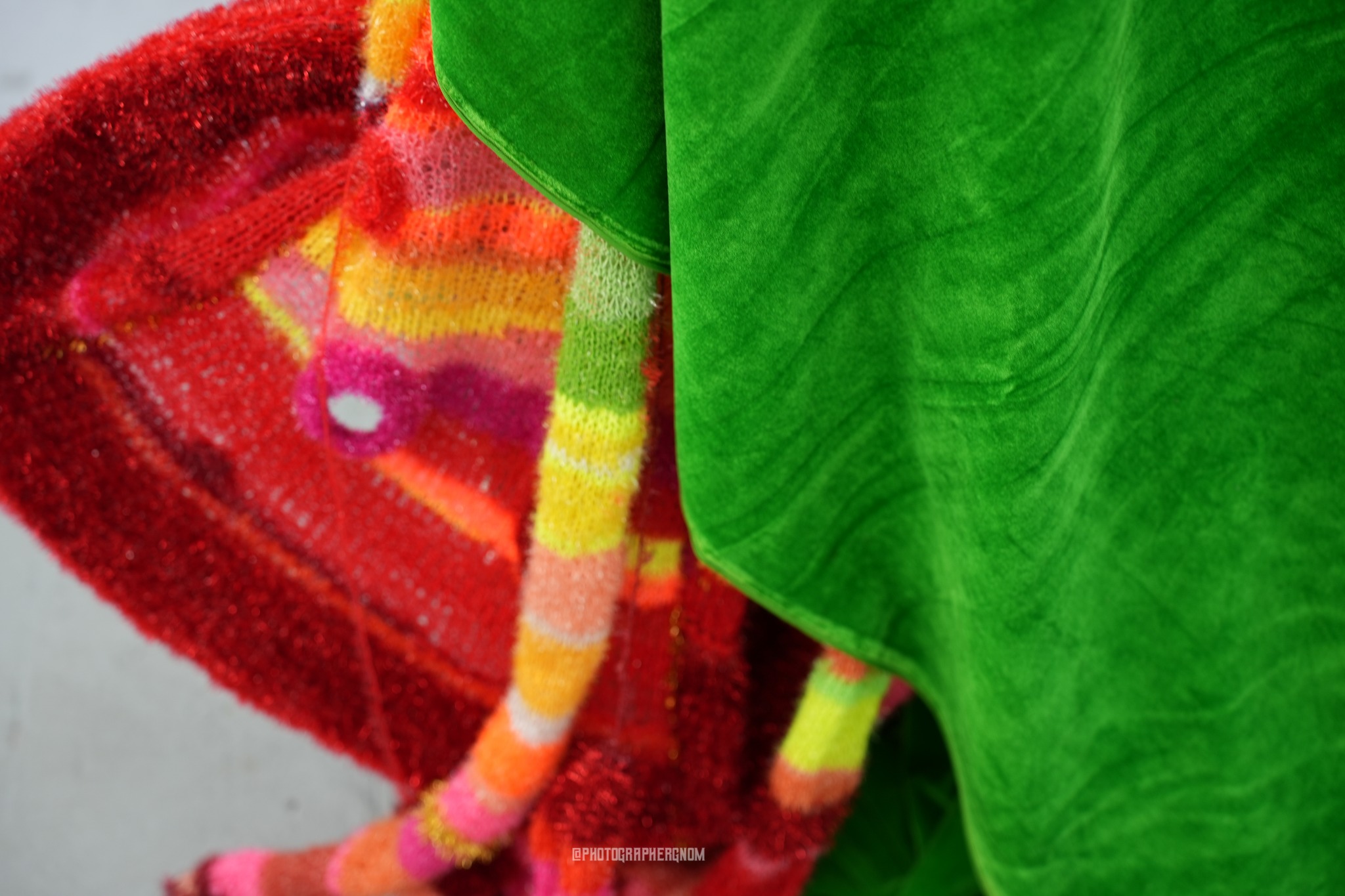 Red and multicoloured knitted costume beside green fabric