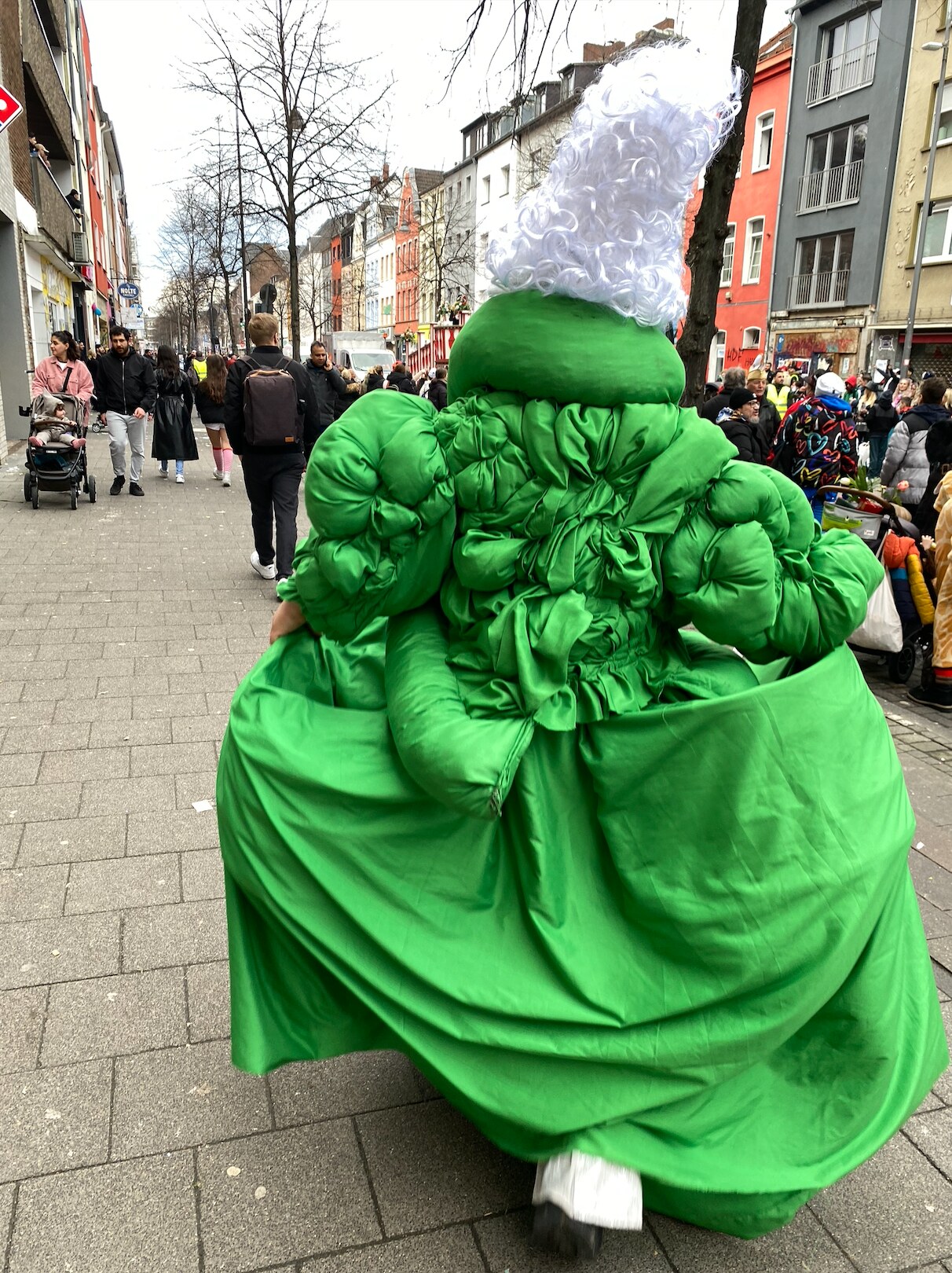 Noblewoman in an exaggerated green coat at carnival
