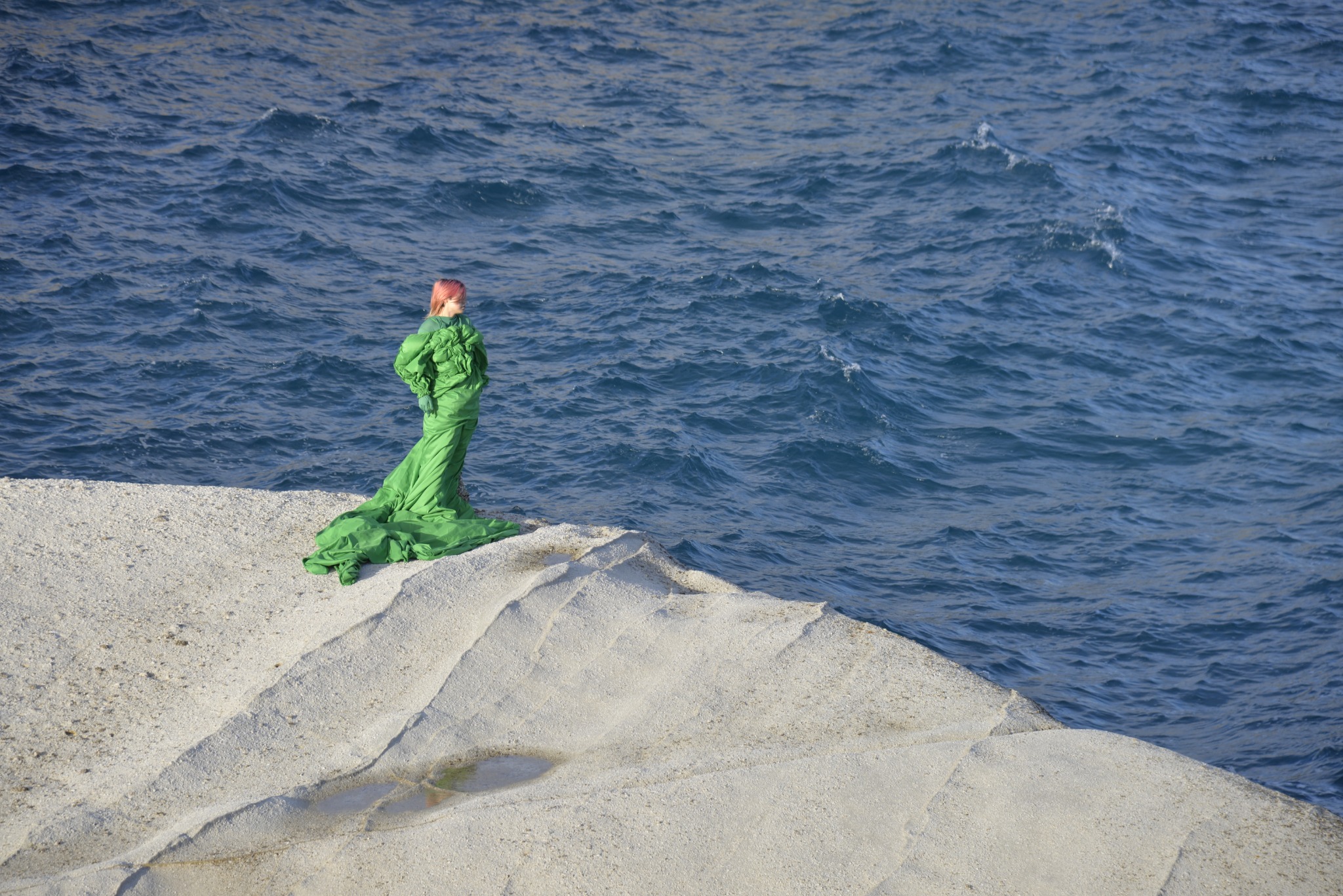 A green-clad Venus figure looking toward the sea