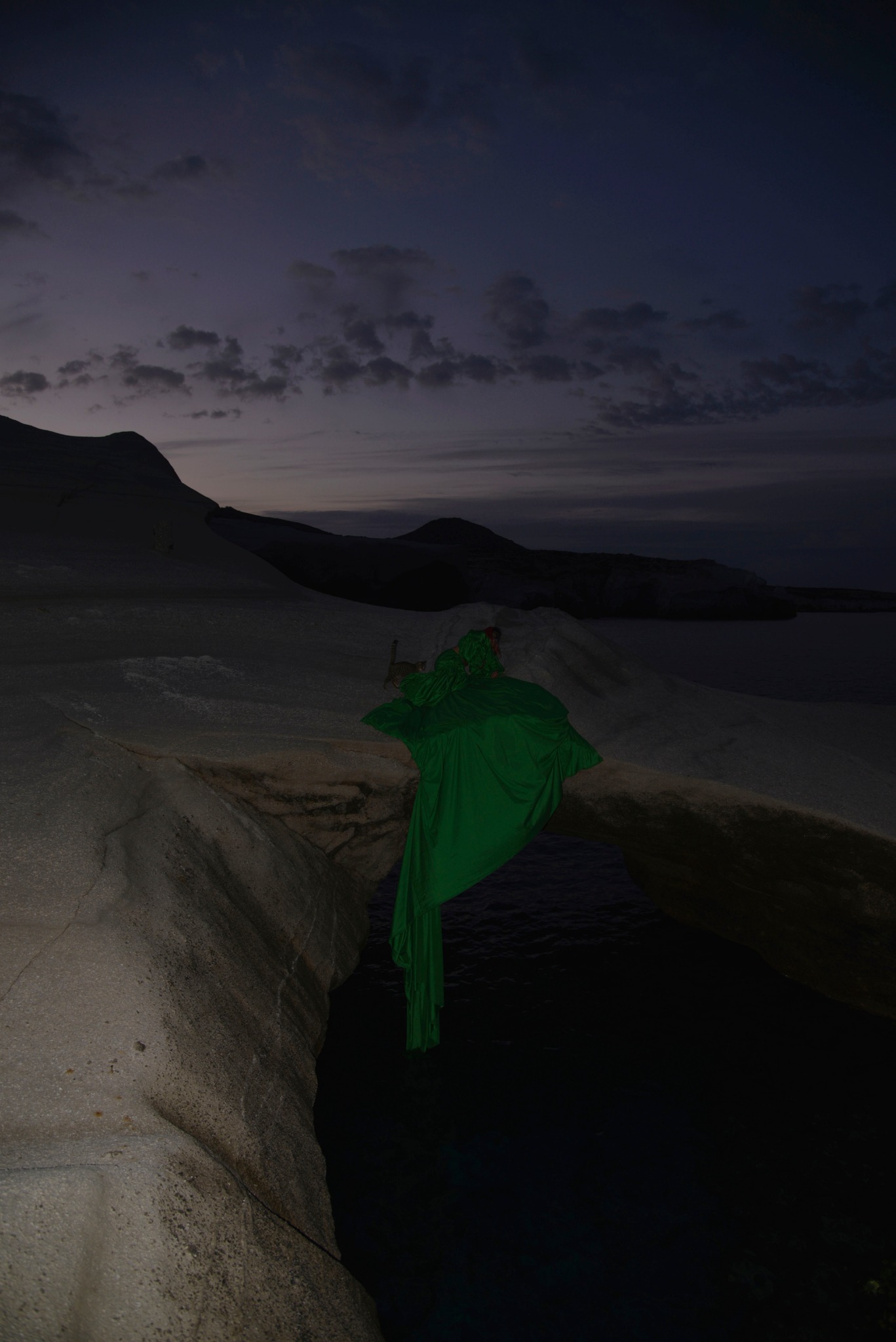 Venus standing in a long green costume among the white rocks