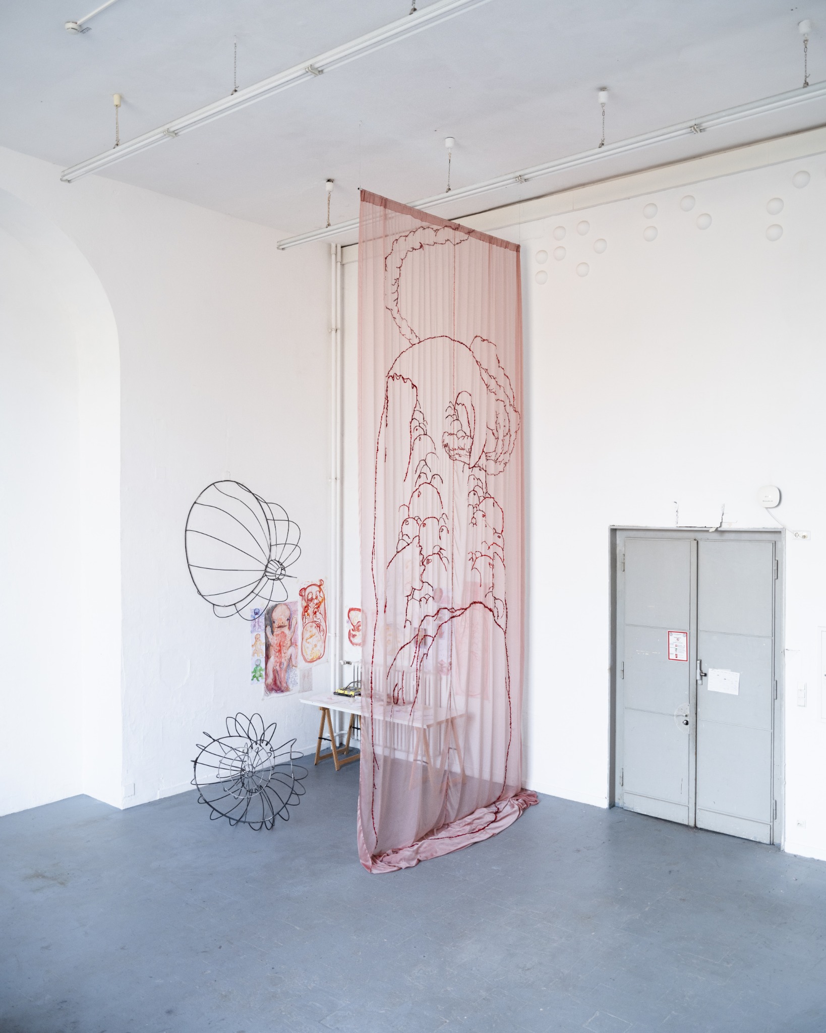 Six Weeks, a large red silk embroidery suspended beside a studio door