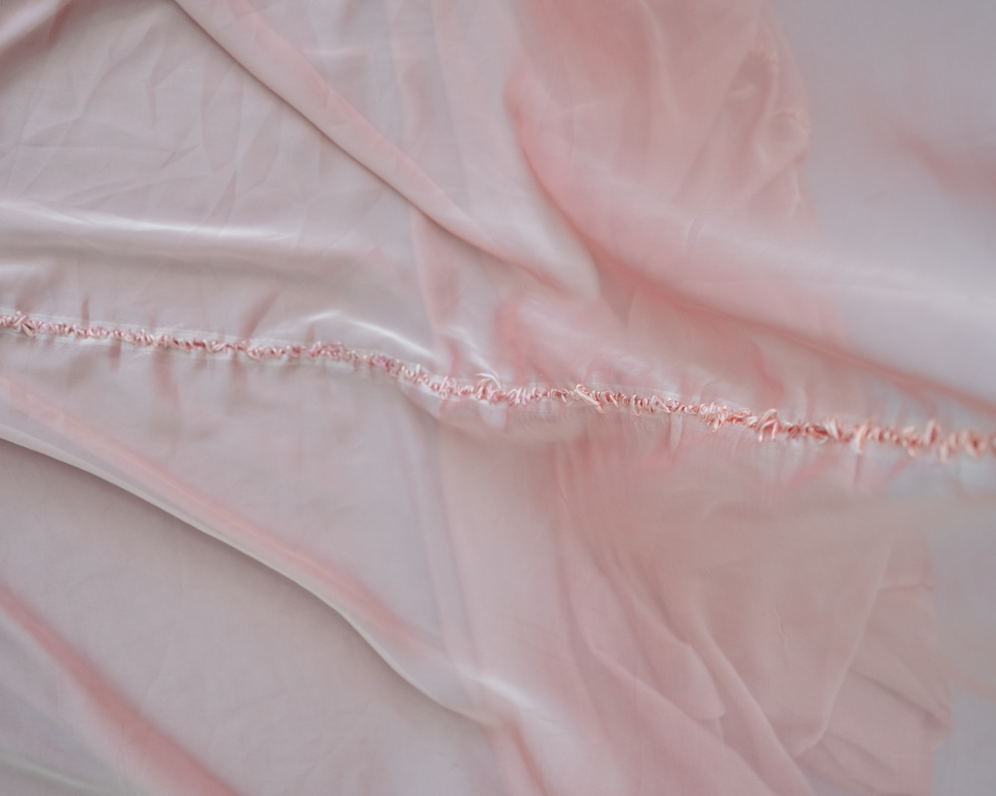 Seam and embroidery detail in pale red organza