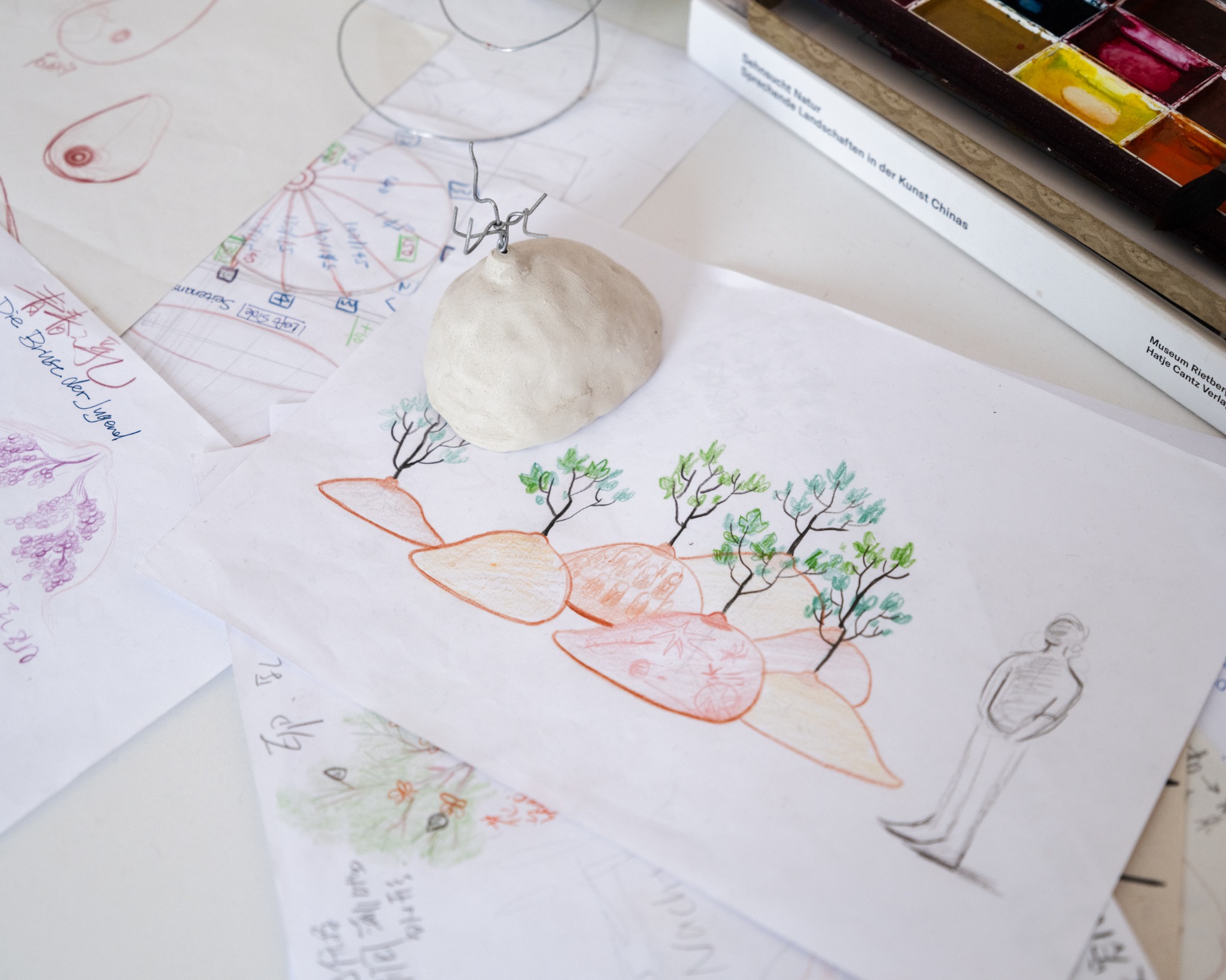 Watercolor and sculptural material tests on a studio table